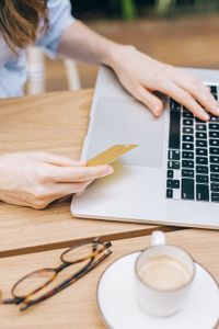 Person holding a credit card while working on laptop