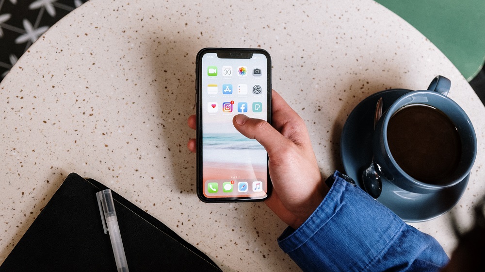 Person using phone on small table with coffee nearby