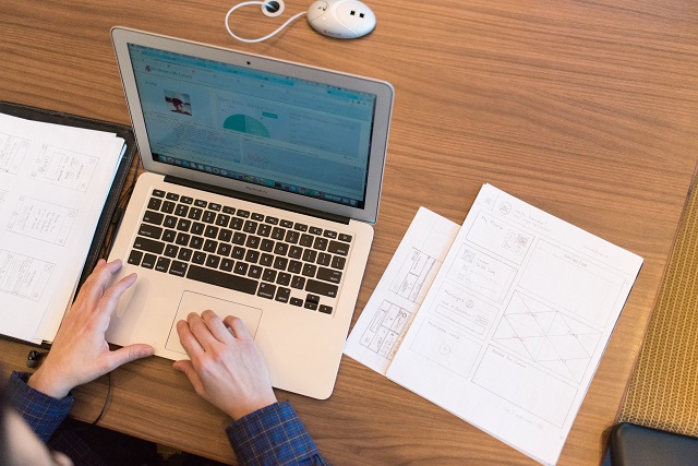 Person using laptop with graphs scattered nearby