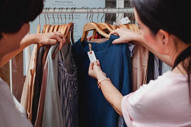 Two people browsing a clothing rack at a store