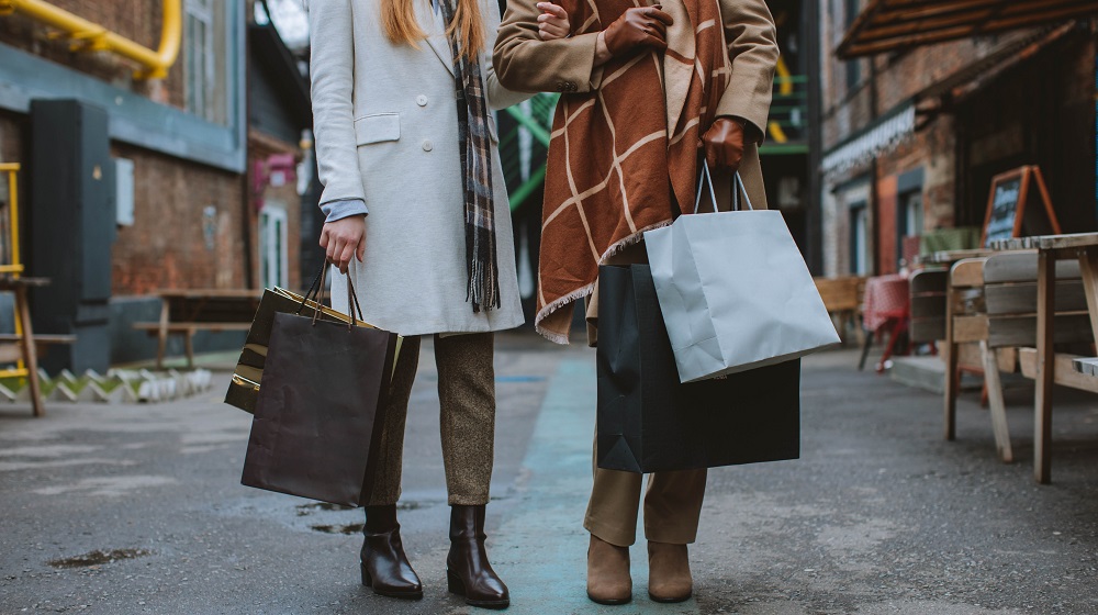 Two people standing on a market street holding shopping bags