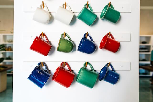 Different colored mugs hanging in neat rows on display