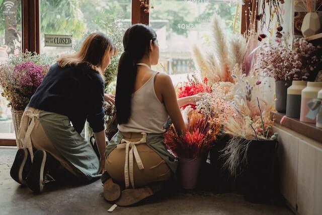 Two store clerks arranging floral display