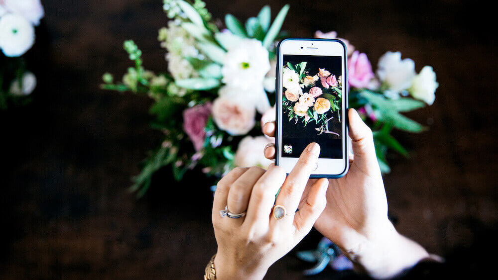 Person taking picture of flower arrangement