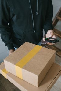 Person holding point of sale device with stack of boxes