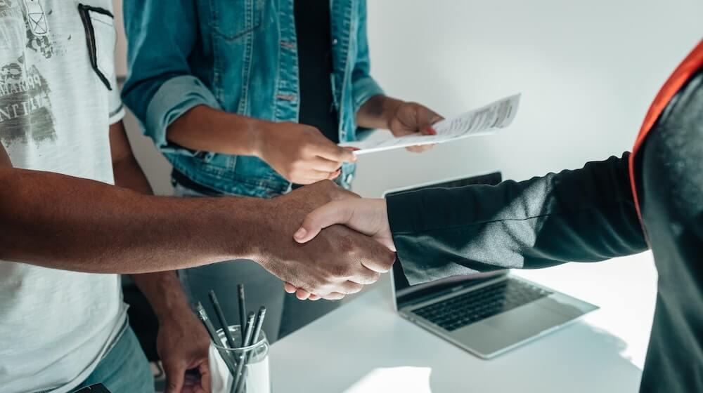Two people shaking hands, reviewing contracts