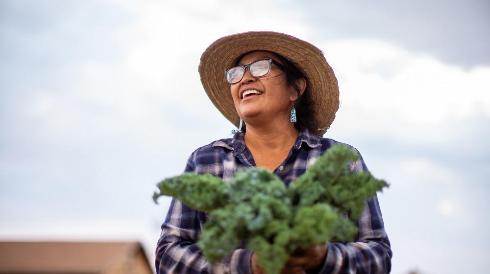 Cherilyn Yazzie of Coffee Pot Farms holding a bunch of kale
