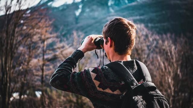 Person hiking and looking through binoculars