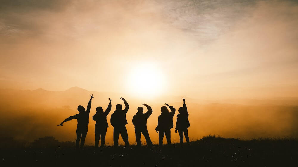 Silhouette of young adults standing on mountainside-2