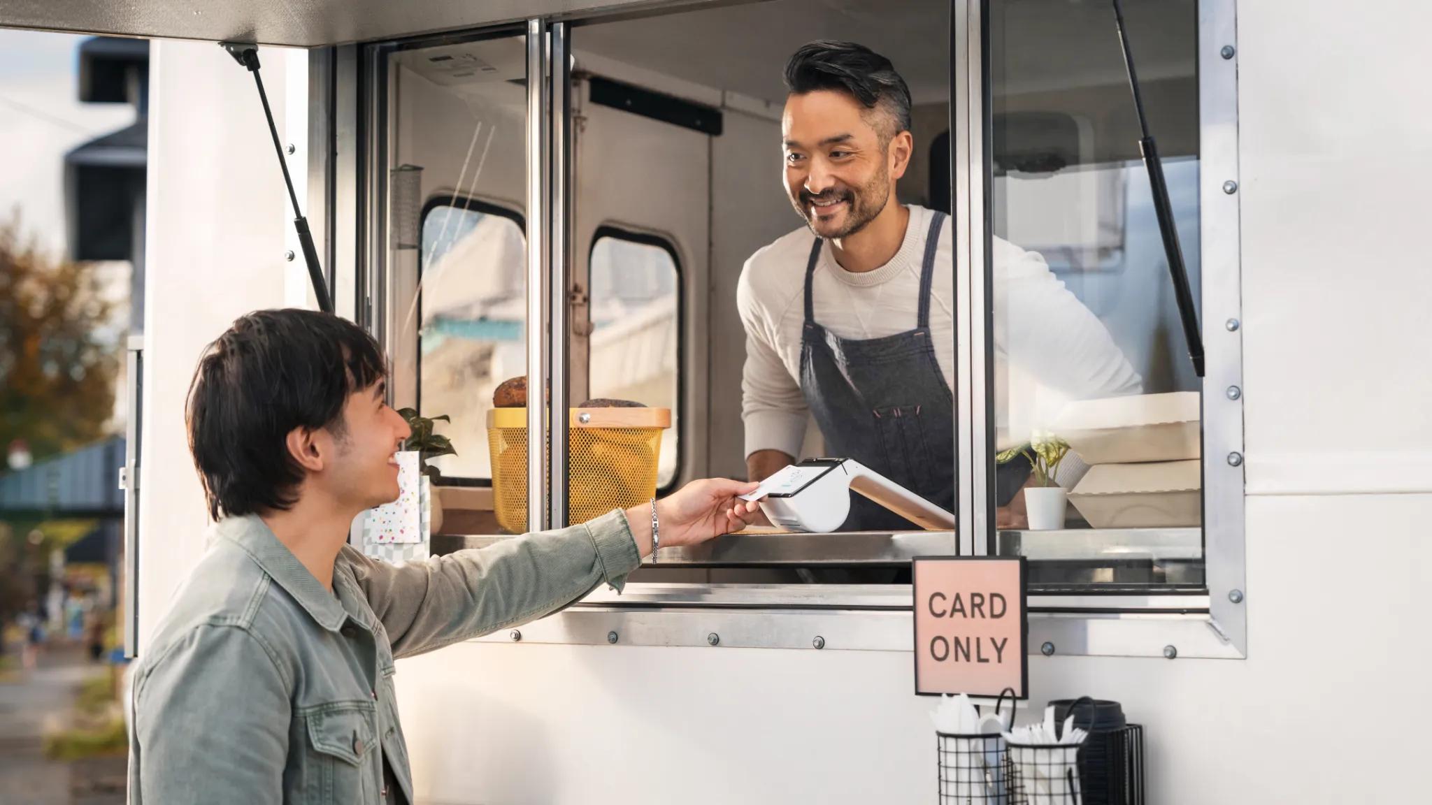 Food truck owner accepting payment via mobile POS system.
