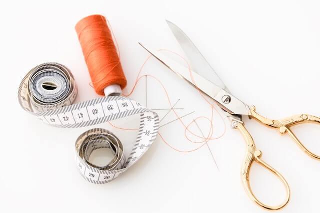 Scissors next to orange thread and measuring tape