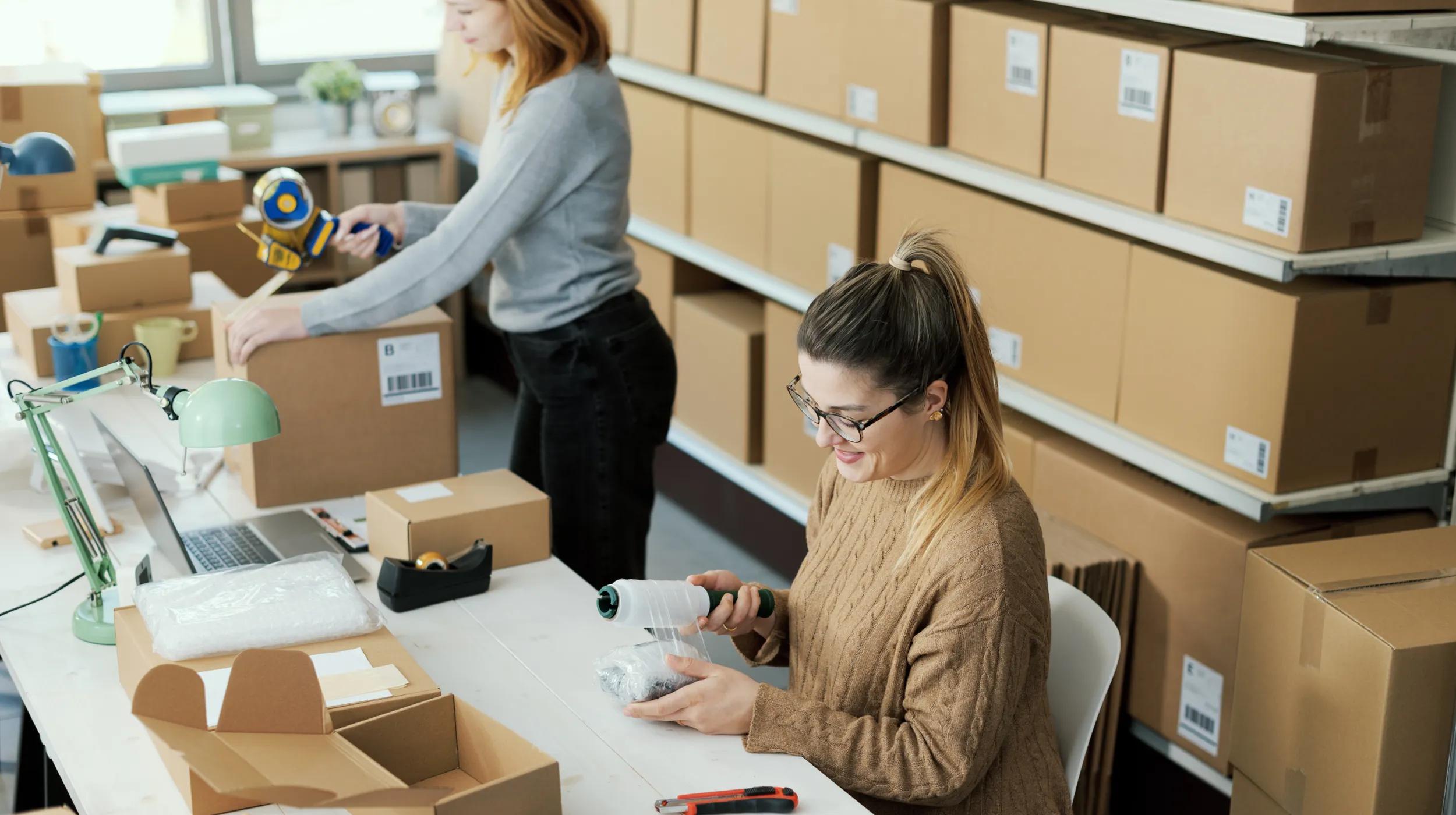 Two women packing sold products in boxes.