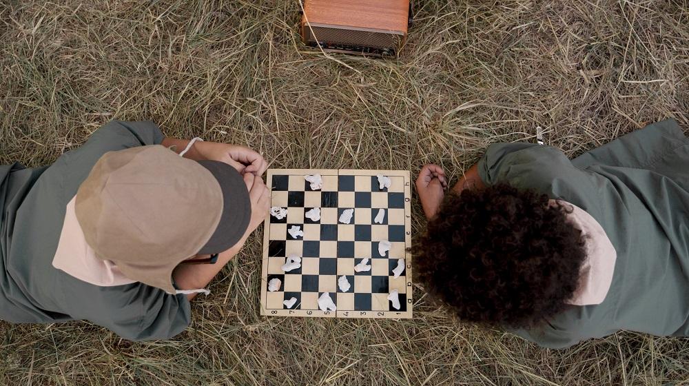 Two children laying on the ground playing chess