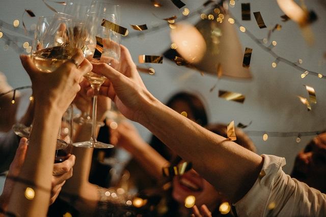 Wine glasses raised in celebration with gold confetti falling from above