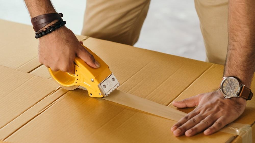Person taping shipping box closed