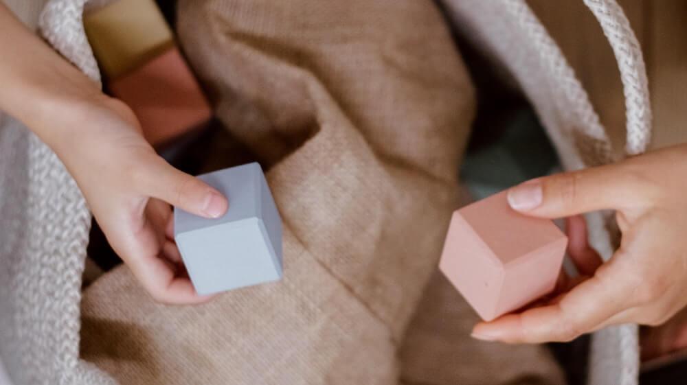 hands holding pink and blue building blocks