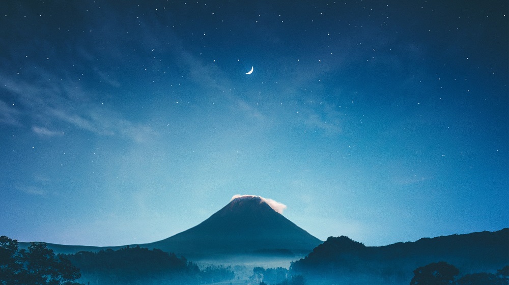 Stars and moon over a mountain landscape