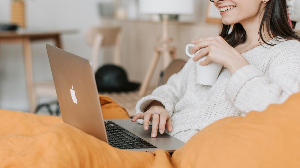 Woman drinking coffee while browsing on laptop
