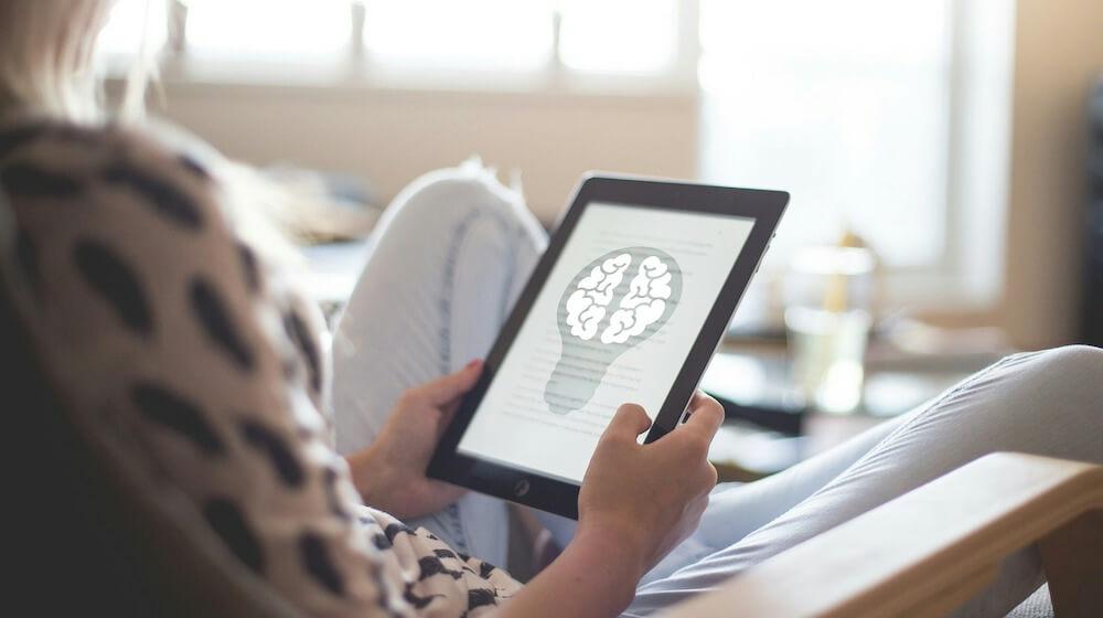 Person looking at image of brain inside lightbulb on tablet