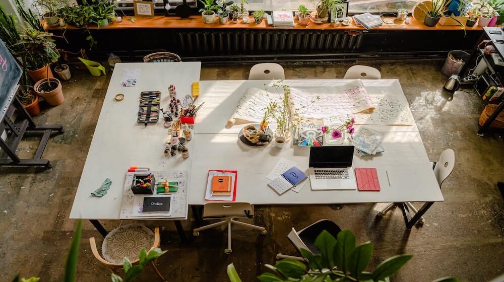 Birds-eye view of work table with design mockups and laptop
