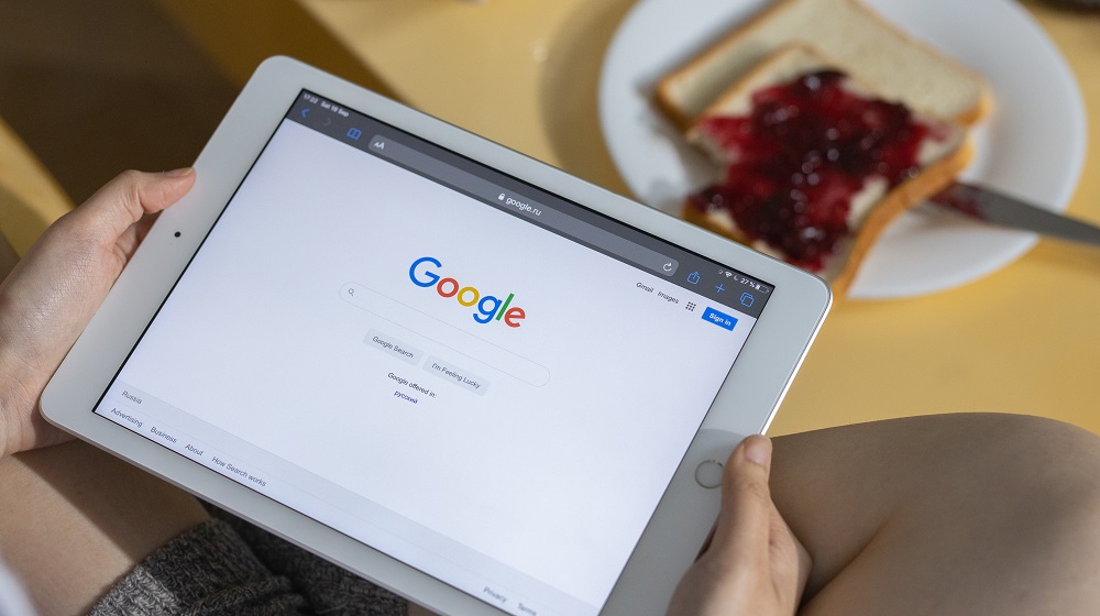 Person sitting cross-legged with an iPad on their lap with Google search screen open
