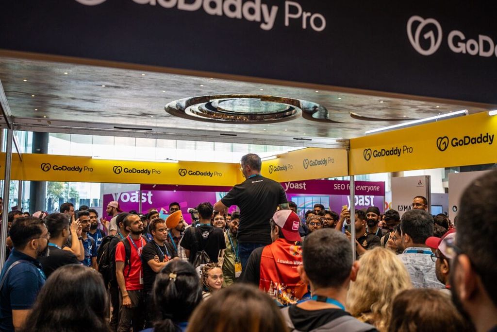 The crowd gathered for the GoDaddy Pro contest giveaway at WordCamp Asia. Seen here is a front view Adam Warner standing to share the results