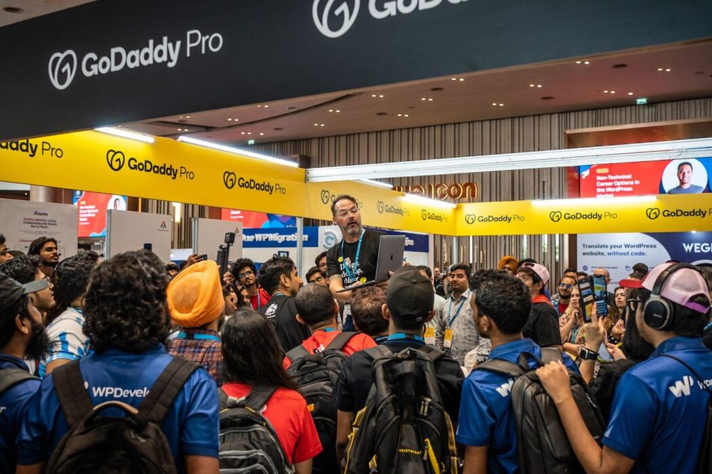 The crowd gathered for the GoDaddy Pro contest giveaway at WordCamp Asia. Seen here is Adam Warner standing to share the results.