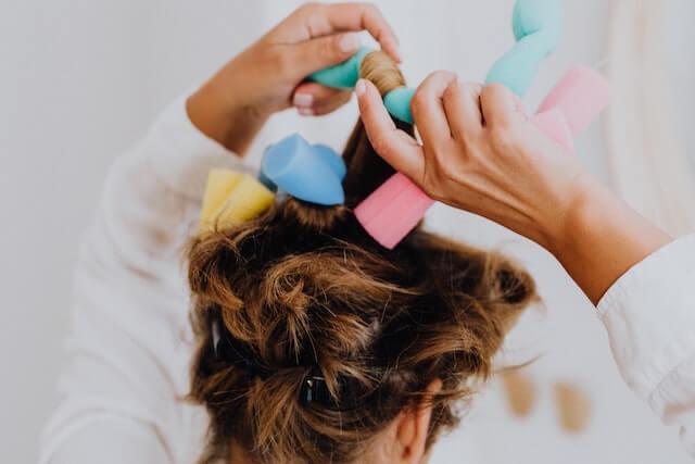 Woman unrolling colorful heatless hair rollers out of her hair