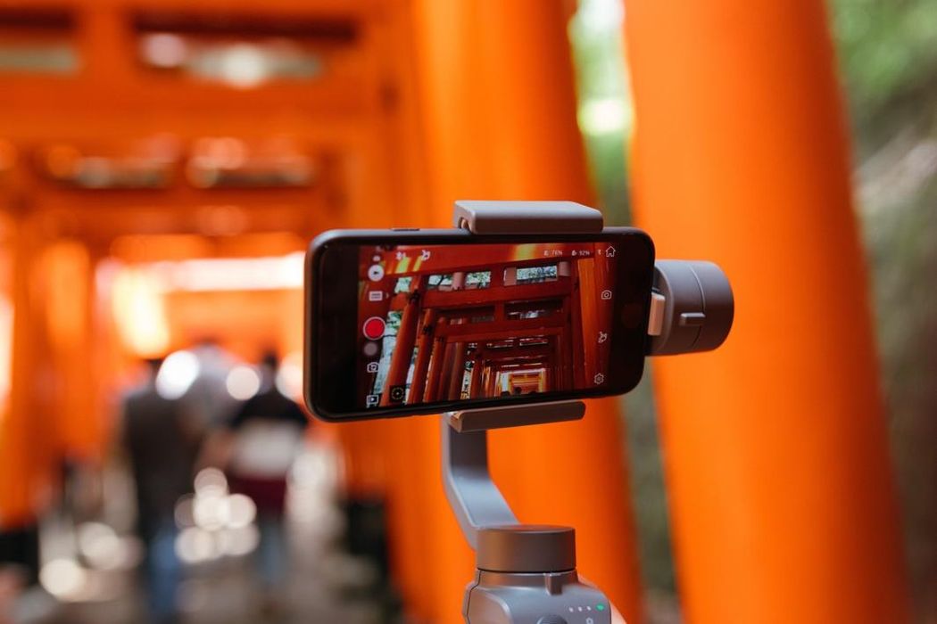 Close-up of mobile phone set to video mode on a selfie stick