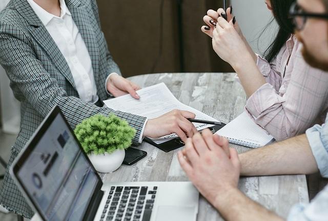 Three people sitting around a desk reviewing legal documents.