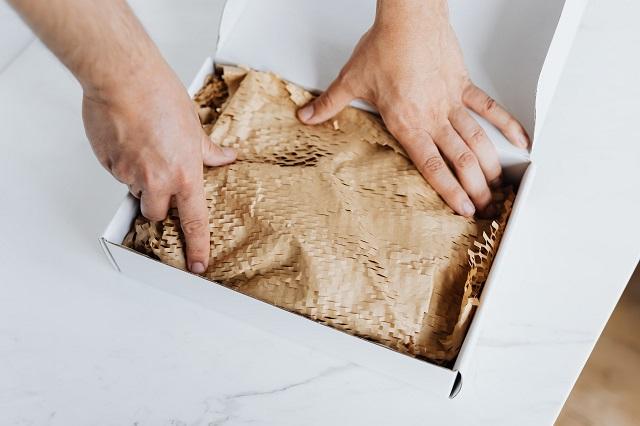 Person packing a shipping box.