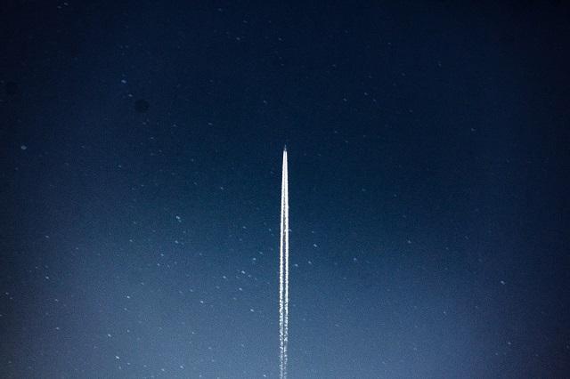 A distant shot of a rocket launch on a dark, starry backdrop.