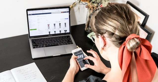 Woman working on an ecommerce website on her laptop while testing on her phone