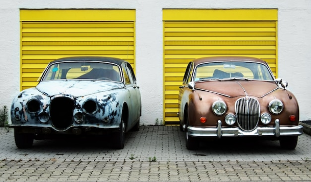 Two cars side by side in front of twin yellow garages