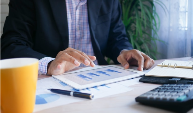 Person sitting at a desk looking over charts that are scattered across a desk