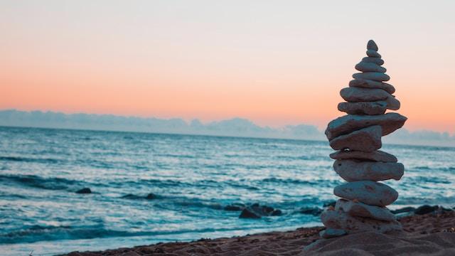 rocks stacked upward on a beach setting at sunset