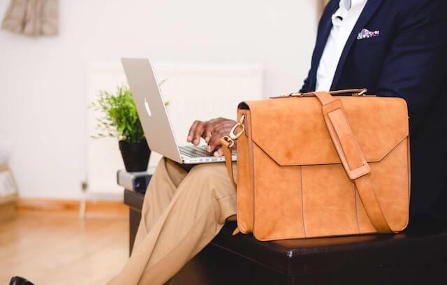 Person typing on laptop with computer bag sitting next to them