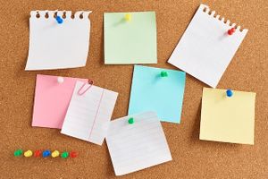 Photo of a cork bulletin board with notes pinned with colorful thumbtacks