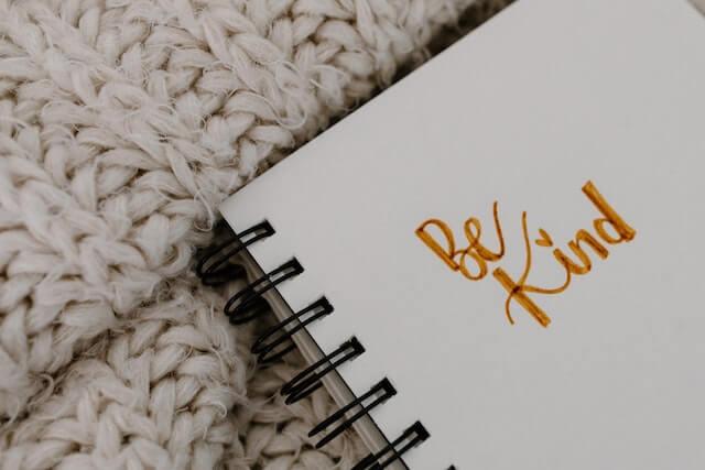 notepad with the words "be kind" written in cursive