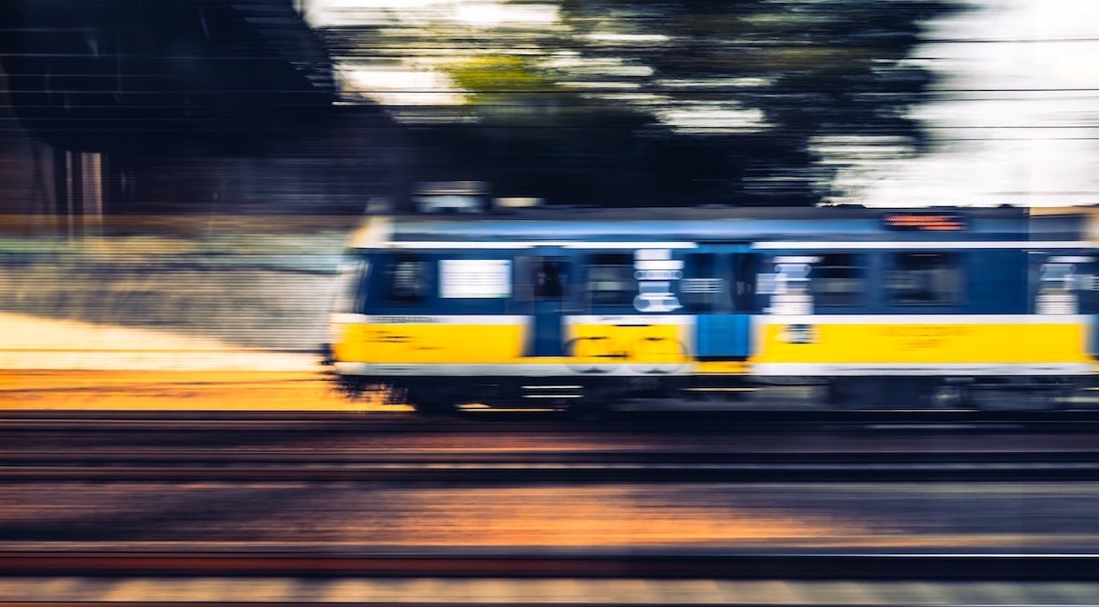 A train moving swiftly along the tracks, creating a blurred effect