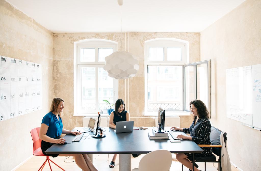 A group of women sitting at a table with computers