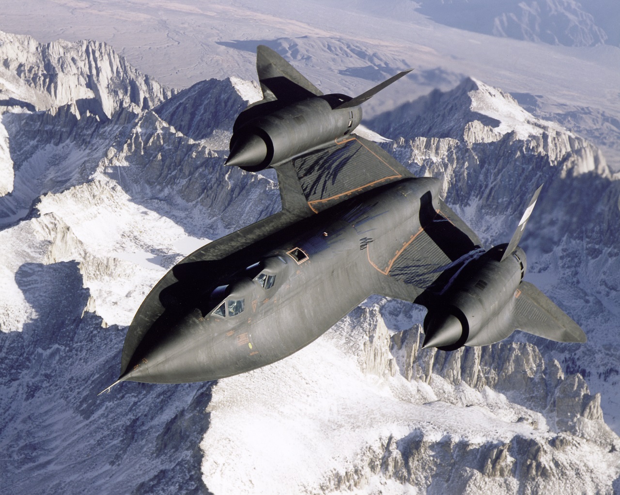 A jet plane flying over snowy mountains