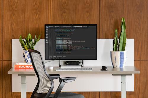 A tidy and modern workstation with a large monitor displaying code for open source projects, a symbol of GoDaddy's commitment to developer communities and open source initiatives.