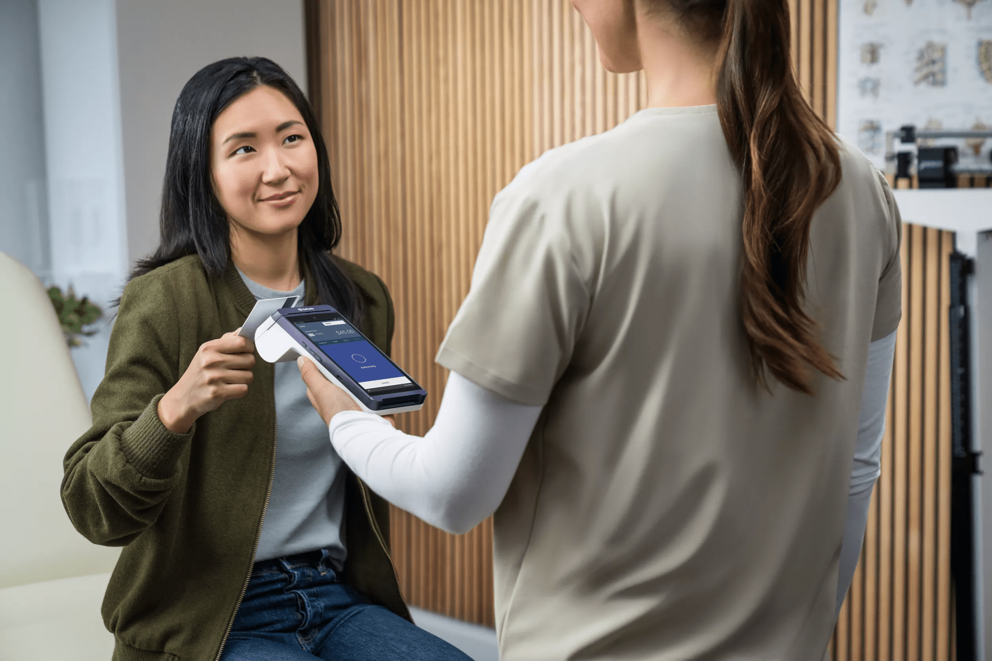 A woman who is a therapist is taking payments from a customer with her portable smart pos terminal