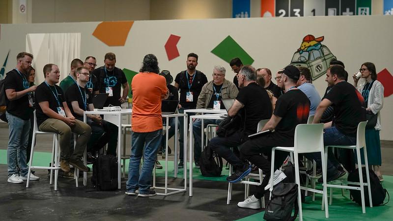 Hosting team table at WCEU contributor day. Javier in the orange seems to be surrounded by GoDaddy and Kinsta