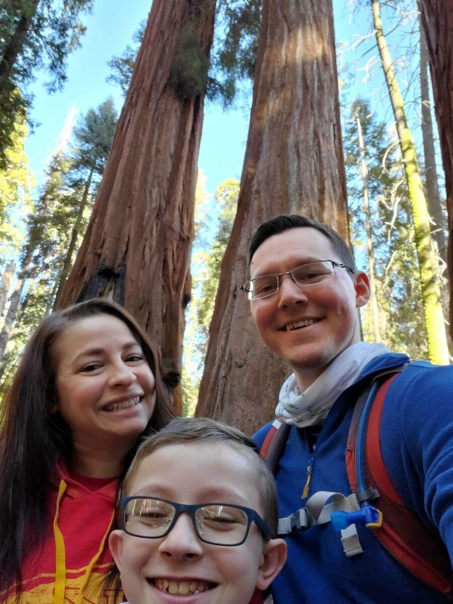 a group of people posing for the camera in front of a tree