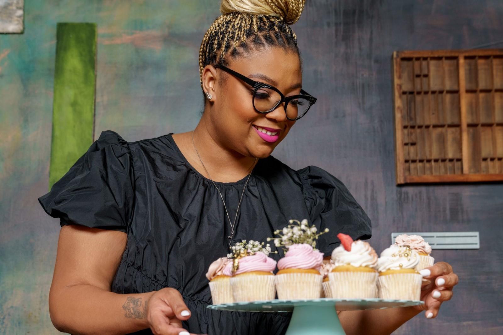 a person holding a tray of cupcakes