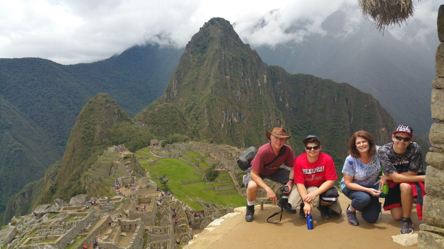 a group of people sitting on a ledge overlooking a valley