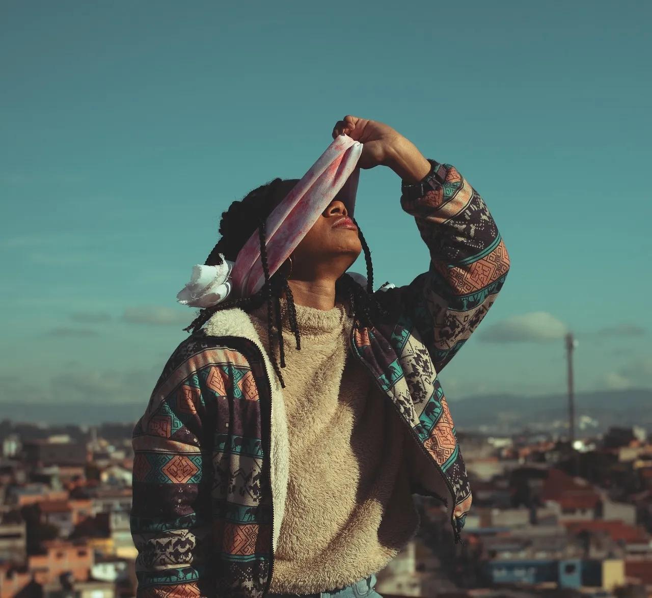 A Person Stands Removing a Blindfold from Their Face