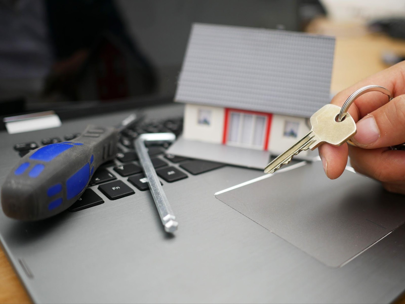 A Housekey Next to a Model House atop a Laptop Suggests Web Security